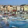 Small boats are docked in front of a small town with buildings connected to one another